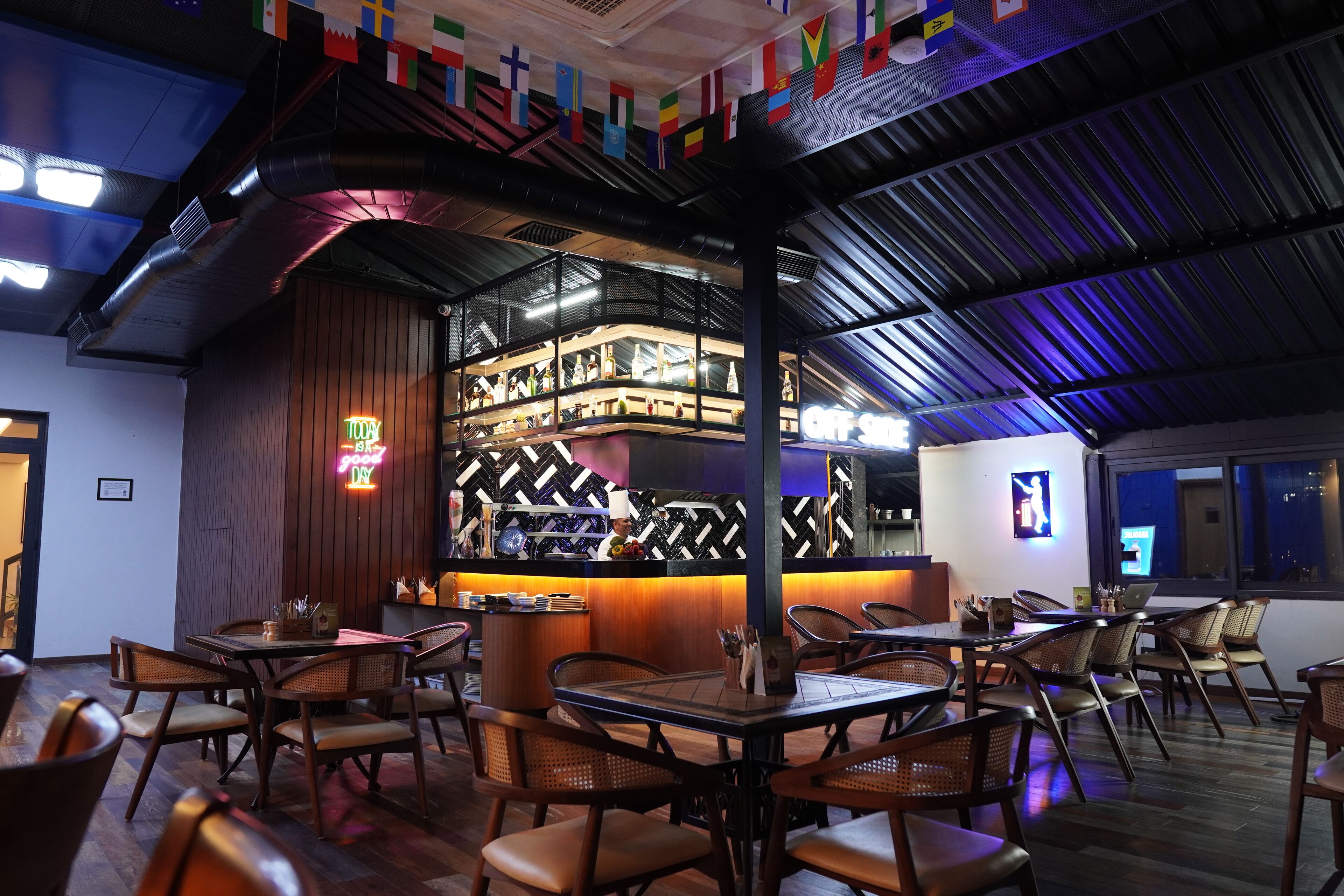 A restaurant with a bar area, wooden furniture, and a herringbone patterned wall.