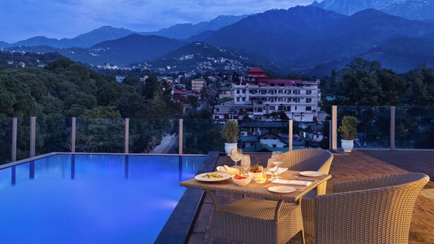 An infinity pool with a dining area overlooking a mountainous landscape. - Infinitea Centric Dharamshala (Dharamshala)