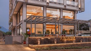 A modern hotel with a stone facade, large windows, and a covered entrance area with a sign reading "INEINITEA." - Infinitea Centric Dharamshala (Dharamshala)