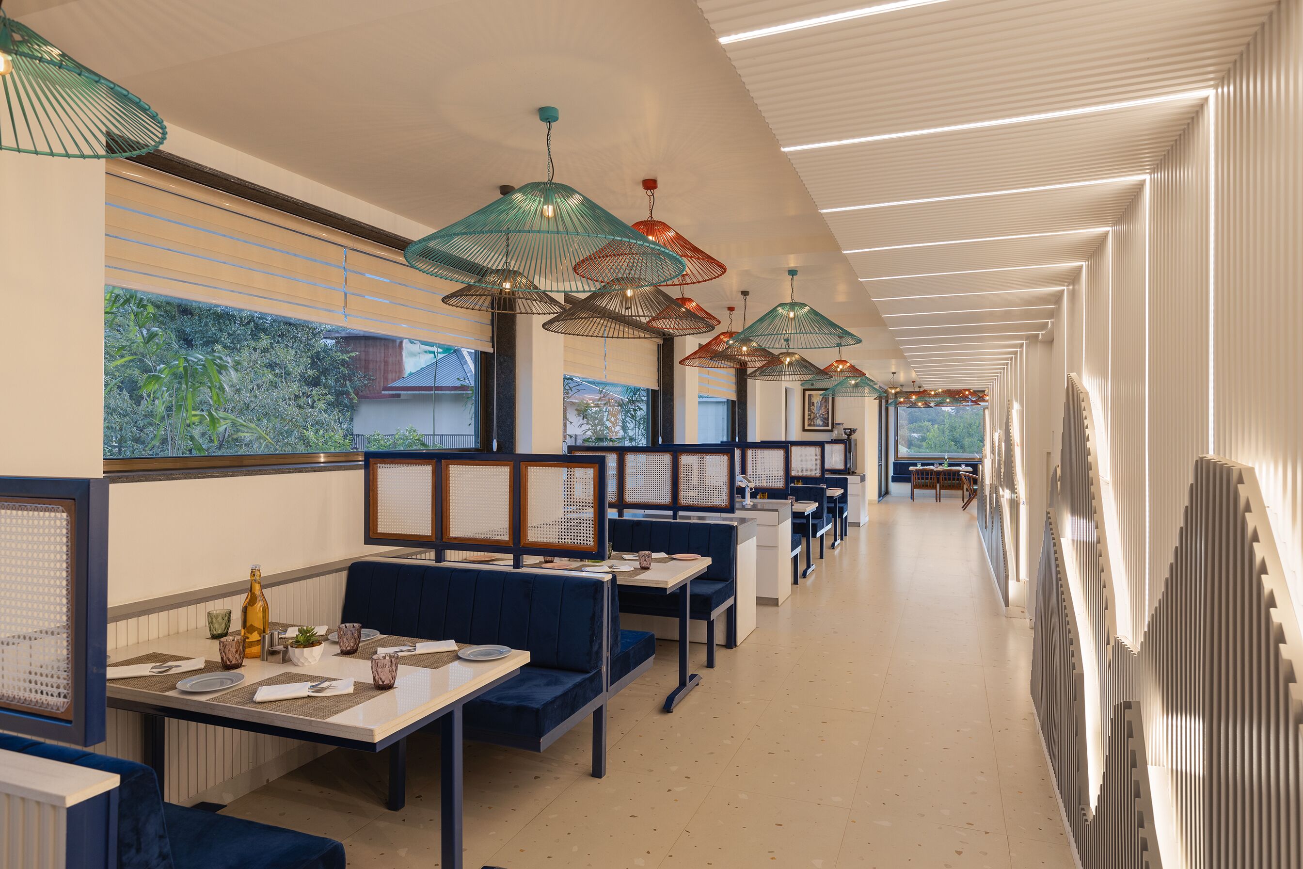 Un restaurante moderno con techos altos, iluminación colgante y una larga barra con asientos.