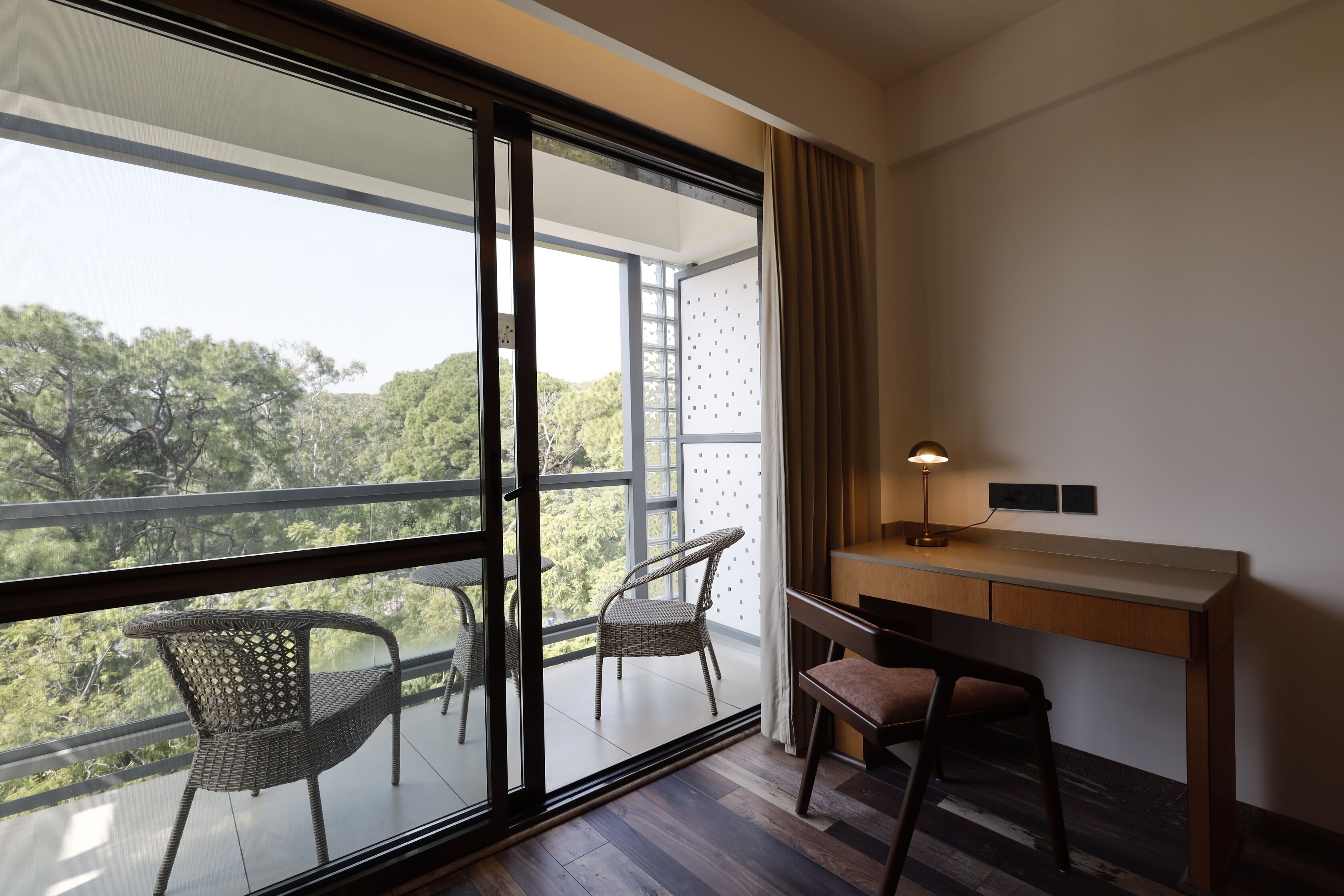 A room with a large window, a desk, two chairs, and a lamp.