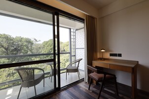 A room with a large window, a desk, two chairs, and a lamp.