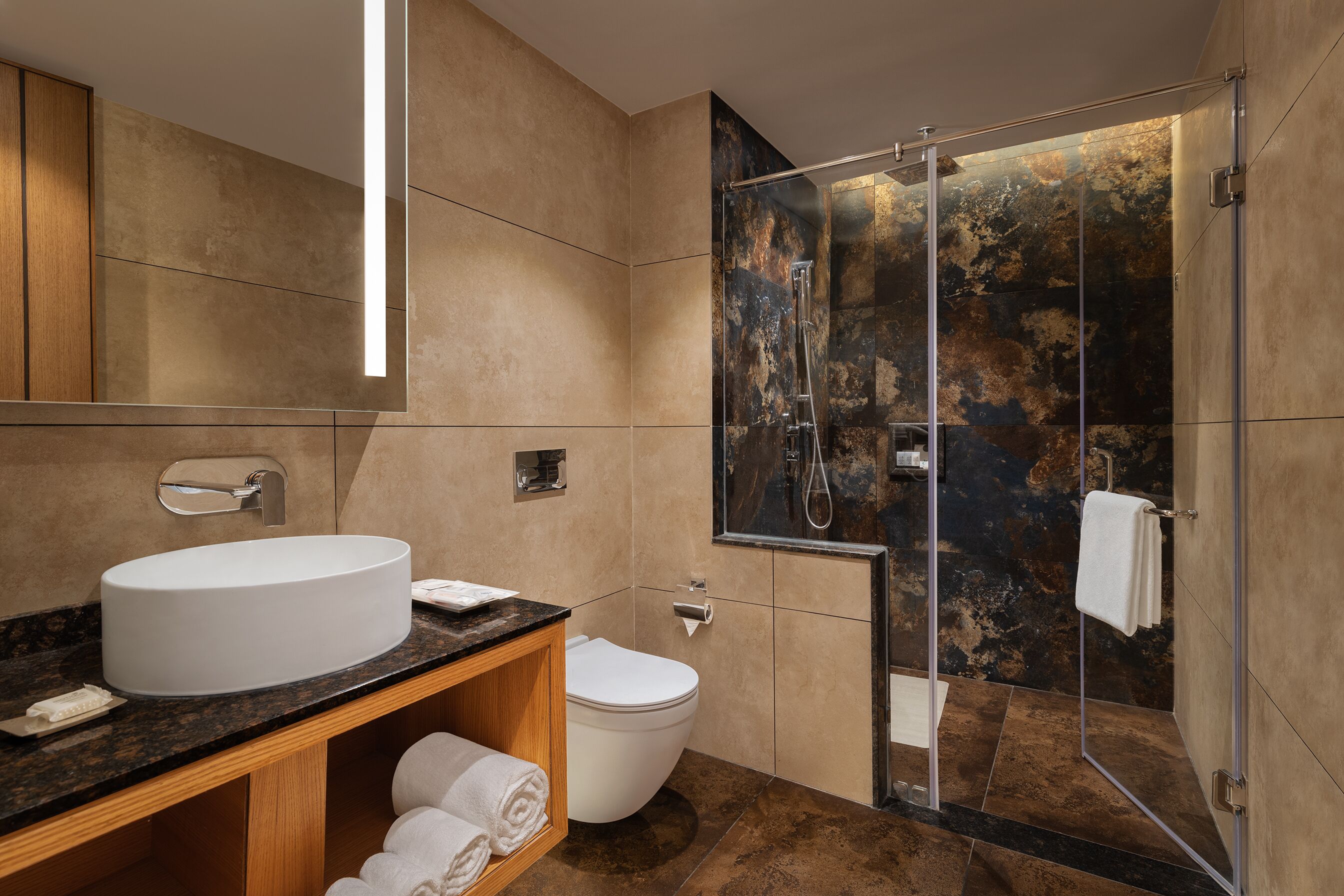 A modern bathroom with a large sink, toilet, and glass-enclosed shower.
