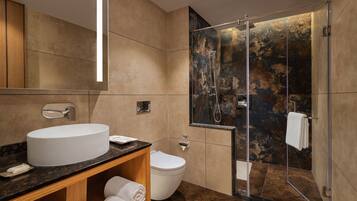 A modern bathroom with a large sink, toilet, and glass-enclosed shower.