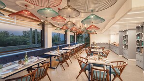 A restaurant with multiple tables and chairs, large windows, and hanging light fixtures. - Infinitea Centric Dharamshala (Dharamshala)