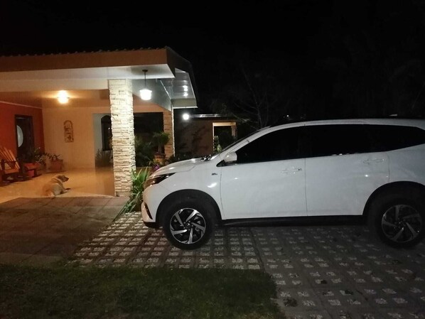 A white SUV parked in front of a house with a stone pillar and a tiled driveway. - A 10 min del Parque de la Fortuna, Apartamento en Zona Tranquila, Parqueo Gratis (La Fortuna)