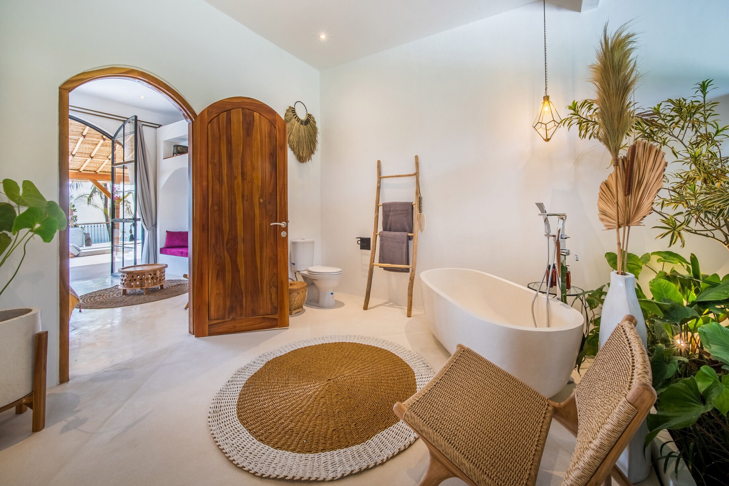 Een moderne badkamer met een vrijstaand bad, een houten deur en een grote spiegel.