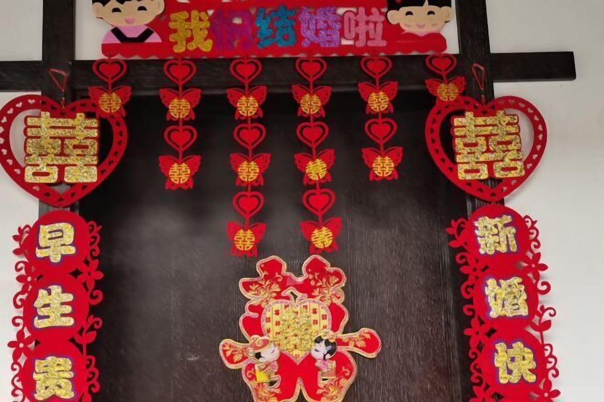 Una pared decorativa con elementos rojos y dorados, que incluyen caracteres chinos y formas de corazón.