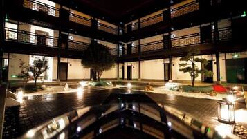 Un patio de varios niveles con una fuente central, rodeado por edificios de diseño arquitectónico tradicional.