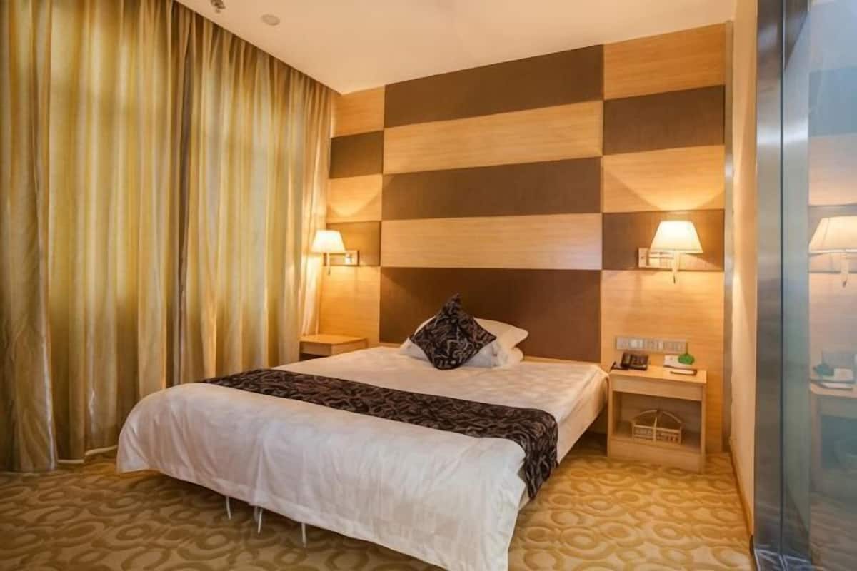 Een hotelkamer met een bed, twee bedlampen, een nachtkastje en een geruit wanddecor.