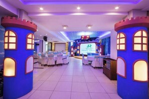 A banquet hall with round tables, a stage with a screen, and castle-themed pillars.