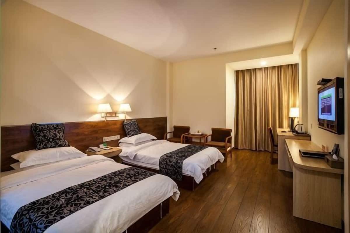 Een hotelkamer met twee bedden, een bureau, een stoel en een televisie.