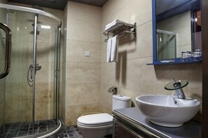 A bathroom with a glass-enclosed shower, a toilet, and a sink with a basin.