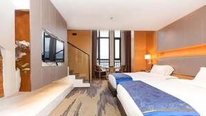 A hotel room with a large bed, a desk, and a TV mounted on the wall. - Ling Jiang Hotel (Yongtai)