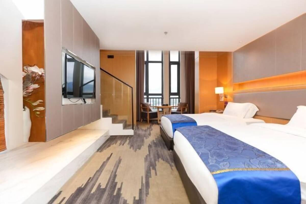 A hotel room with a large bed, a desk, and a TV mounted on the wall.