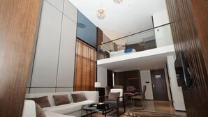 A modern living room with a white sofa, a coffee table, and a glass railing overlooking a lower level. - Ling Jiang Hotel (Yongtai)