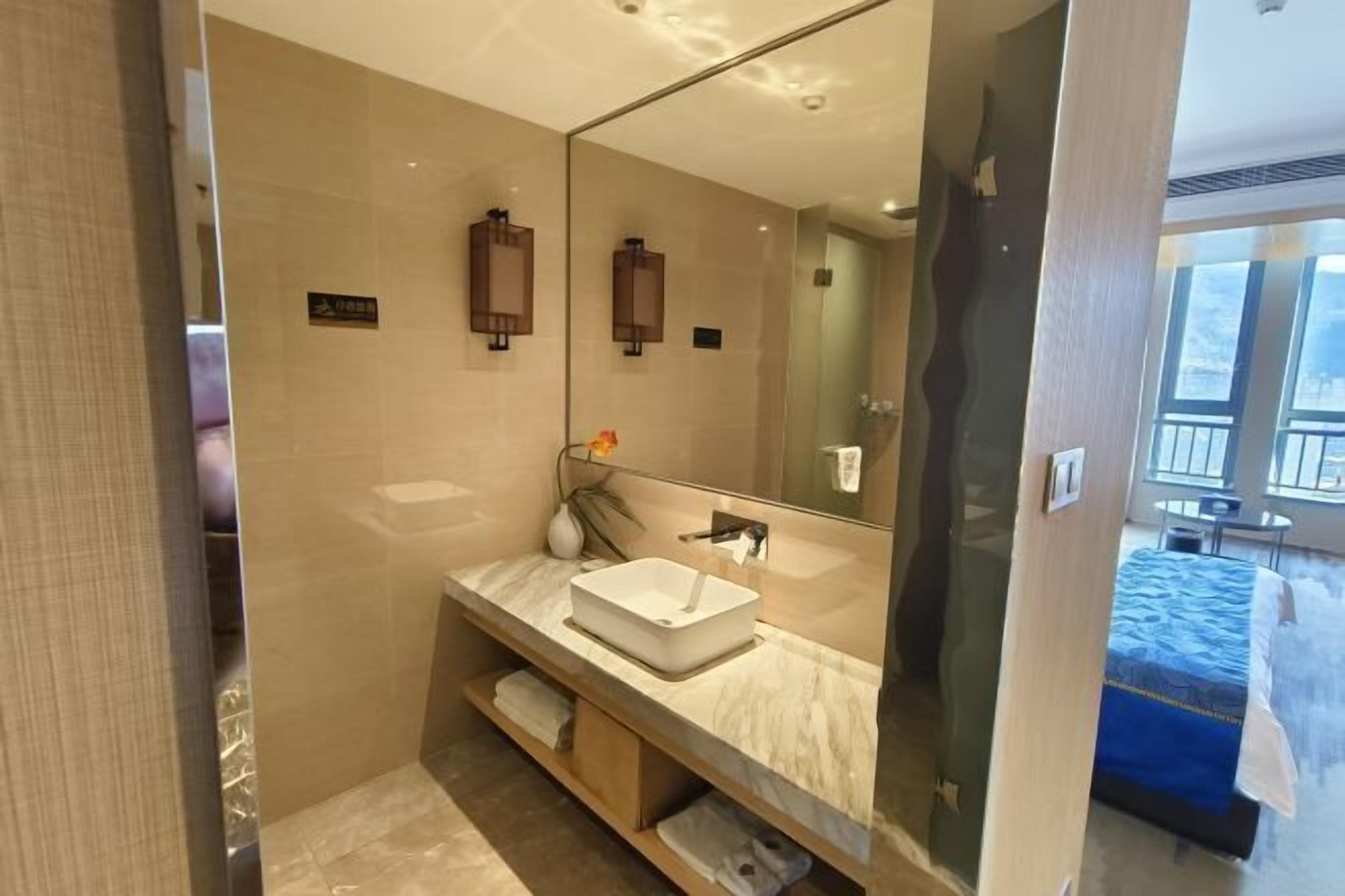 A modern bathroom with a large mirror, a white sink, and a towel rack.