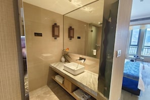 Un baño moderno con un espejo grande, un lavabo blanco y un perchero para toallas.