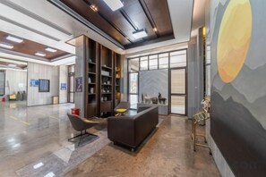 A modern lobby with a reception desk, seating area, and a large mural. - Ling Jiang Hotel (Yongtai)