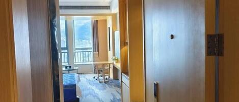 Habitación de hotel con una ventana grande, una cama, un escritorio y una silla.