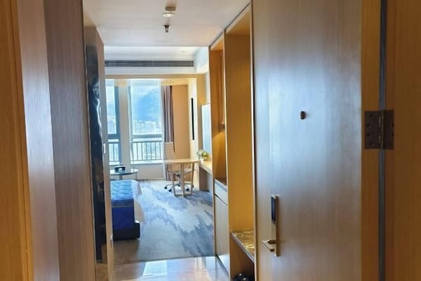 Habitación de hotel con una ventana grande, una cama, un escritorio y una silla.