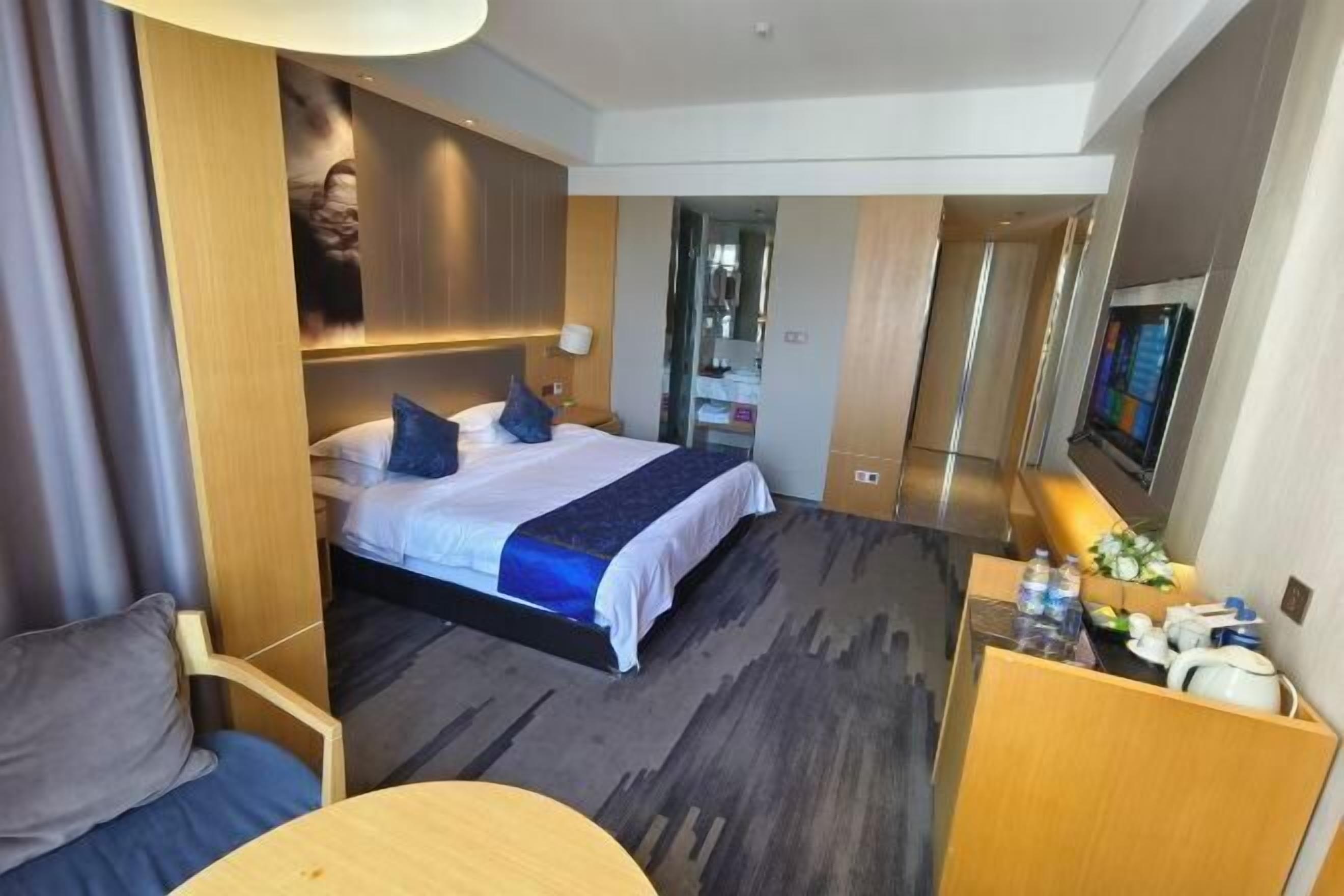 A hotel room with a bed, a desk, a chair, and a TV.