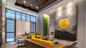 A modern reception area with a wooden reception desk, a large painting of a mountain and sun, and a view of a cityscape through large windows. - Ling Jiang Hotel (Yongtai)