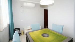 Een kamer met een groene tafel, twee blauwe stoelen, een wit plafondlamp en een deur.