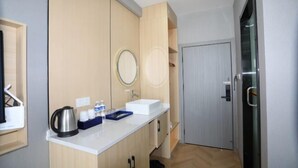 Een moderne badkamer met een witte wastafel, een spiegel en een waterkoker op het aanrecht.