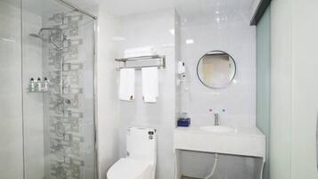 A modern bathroom with a glass shower enclosure, a toilet, a sink with a mirror, and a towel rack.