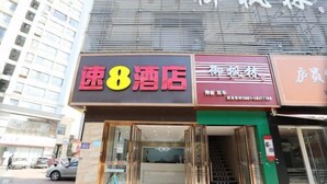 A hotel with a prominent sign reading "速8酒店" and a visible staircase leading to the entrance.