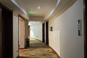 A hotel hallway with carpeted floors, doors, and a wall-mounted light fixture. - Nanning Qinglin Holiday Hotel (Nanning)