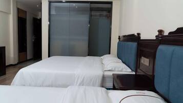 Ein Hotelzimmer mit zwei Betten, einem Schiebetürenschrank und einem kleinen Nachttisch.