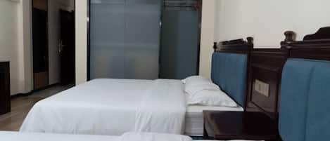 A hotel room with two beds, a sliding door closet, and a small bedside table.