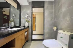 Une salle de bain moderne avec un grand miroir, deux vasques et des toilettes.