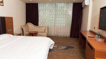 Ein Hotelzimmer mit Bett, Sofa, kleinem Tisch, Schreibtisch und Fernseher.