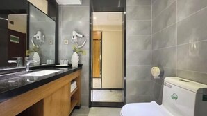 Et moderne badeværelse med en sort bordplade, træskab og et stort spejl samt toilet.