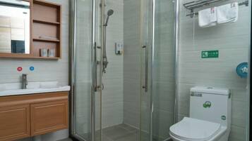 Un baño moderno con ducha acristalada, lavamanos blanco y retrete.