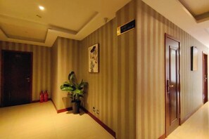 A hotel corridor with striped walls, a potted plant, and a fire extinguisher. - Hai'an Yueshe Boutique Hotel (Yueqing)