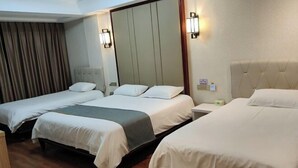 Een hotelkamer met drie bedden, een houten vloer en een grote spiegel aan de muur.