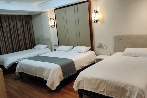 Ein Hotelzimmer mit drei Betten, Holzboden und einem großen Spiegel an der Wand.