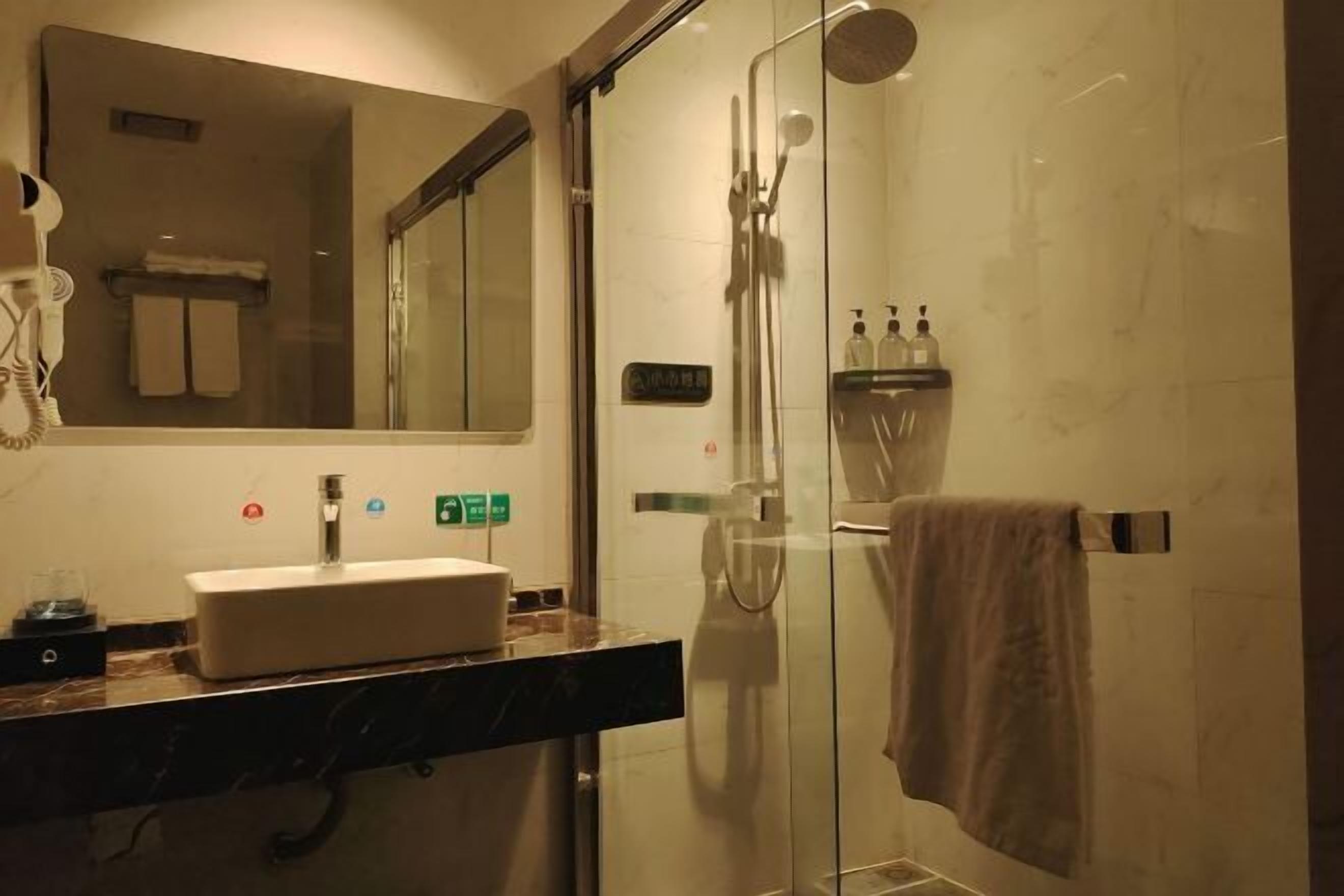 A bathroom with a glass-enclosed shower, a sink with a mirror above it, and a towel rack.