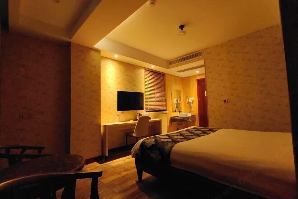A hotel room with a bed, desk, chair, and a television.
