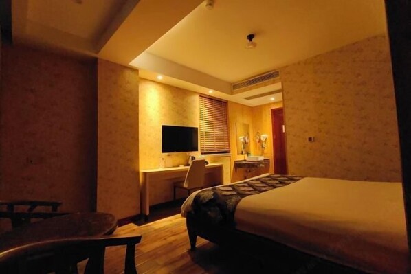 A hotel room with a bed, desk, chair, and a television.