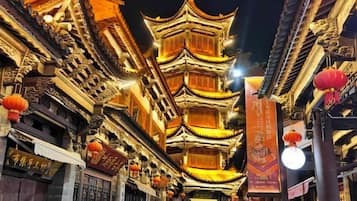 A traditional multi-tiered pagoda with ornate carvings and lanterns, surrounded by buildings with signage.
