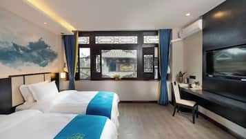 A hotel room with two beds, a desk, a TV, and a window with a view of traditional architecture.