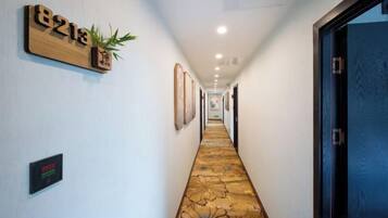 A hotel hallway with a carpeted floor, framed pictures on the walls, and a door on the right.