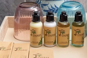 Four bottles of black tea body lotion and a large vase on a table. - Qinqi Inn (Kunming)
