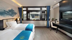 A hotel room with two beds, a desk, a TV, and a window with traditional Chinese window design. - Qinqi Inn (Kunming)