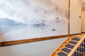 A staircase with a wooden handrail and blue steps, leading to a room with a large wall mural of a snowy landscape. - Qinqi Inn (Kunming)